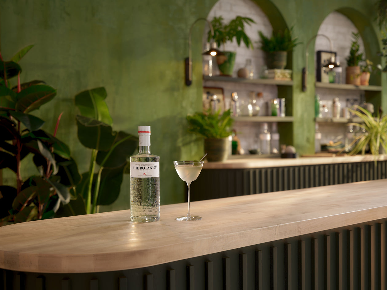 A lifestyle photo of a Botanist bottle and a cocktail on a bar countertop