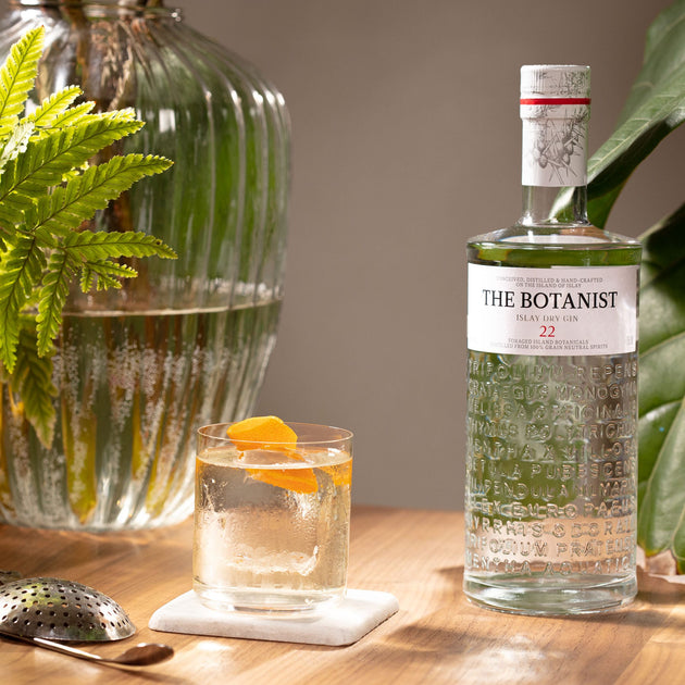 A lifestyle photo of a Botanist bottle close to a cocktail