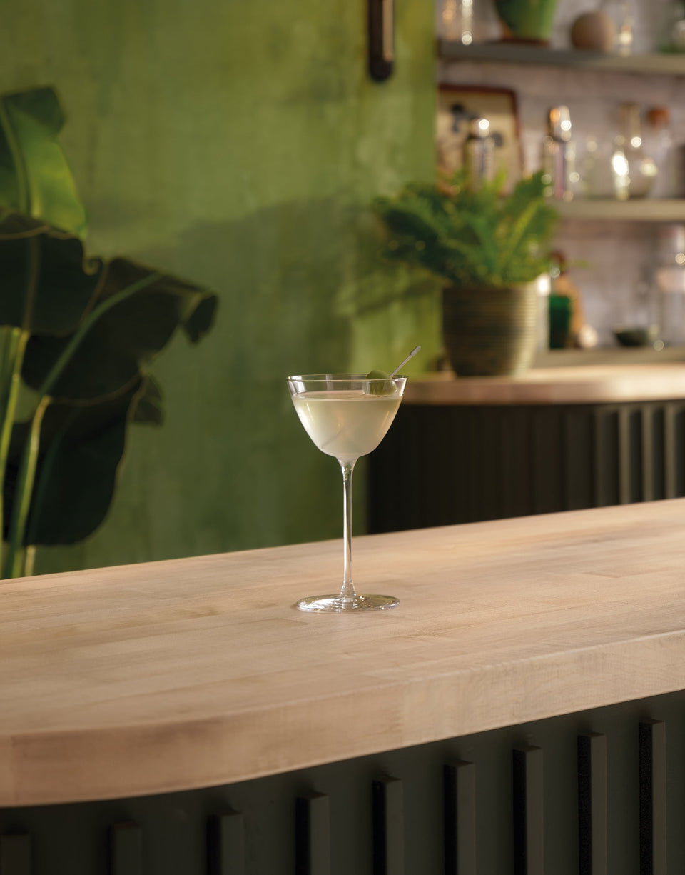 A lifestyle photo of a Botanist bottle and a cocktail on a bar countertop