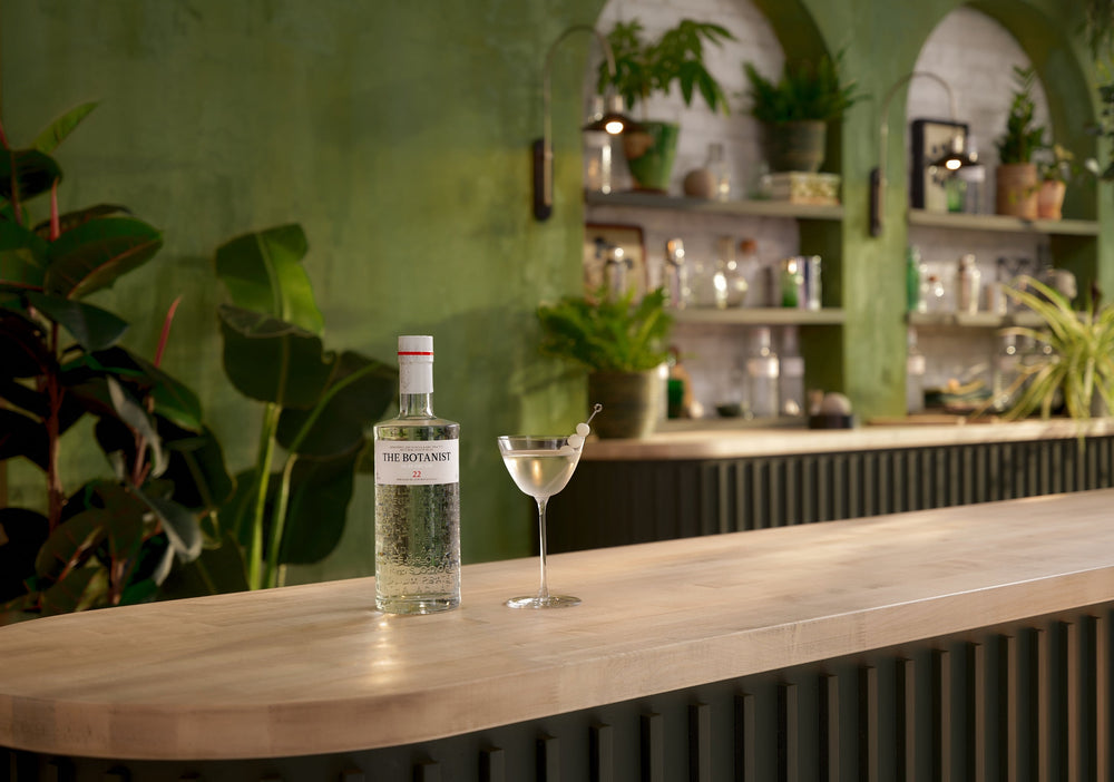 A lifestyle photo of a Botanist bottle and a cocktail on a bar countertop