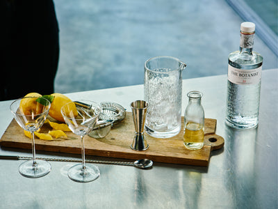 A lifestyle photo depicting a bottle of Botanist, cocktail glasses and cocktail preparing set