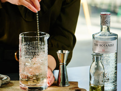 A photo of a person preparing a Botanist cocktail in embossed glass